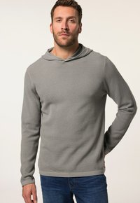 Grauer langärmliger Kapuzenpullover aus strukturiertem Stoff, mit lockerem Schnitt und gerippten Bündchen, kombiniert mit blauen Jeans.
