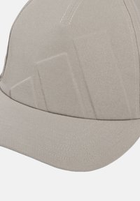 Casquette gris clair avec une surface texturée, dotée d'une visière courbée et de détails de couture subtils. Le design est élégant et ajusté.