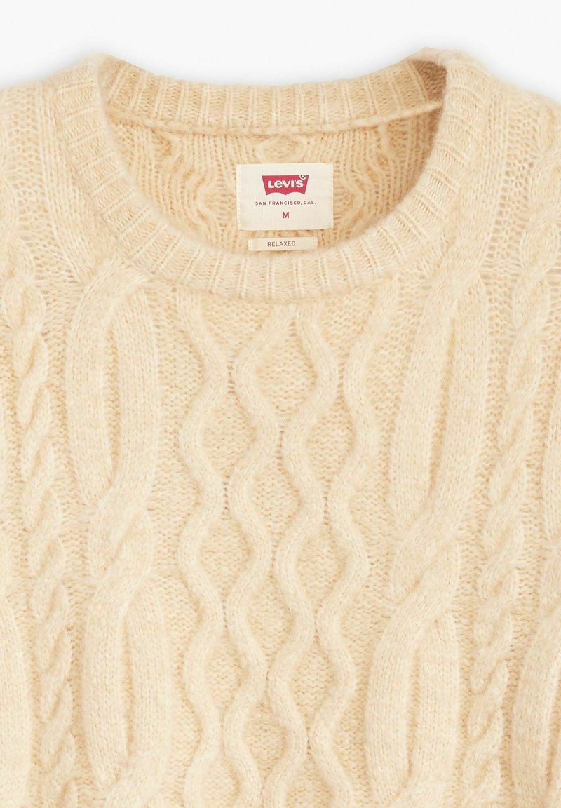 Sweter dzianinowy w kremowym kolorze z wzorem warkocza, prążkowanym okrągłym dekoltem oraz metką wskazującą rozmiar M i markę Levi's.