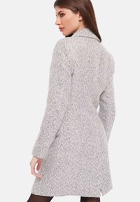 Cappotto da donna a pattern houndstooth in grigio chiaro e bianco, con un design strutturato, maniche lunghe e una singola fessura sul retro.