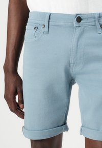 Lysblå denimshorts med optrullet kant, udstyret med forlommer, metalknaplukning og et glat, struktureret stof.