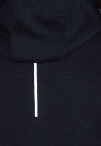 Pulkaover bleu foncé avec capuche, présentant une texture lisse et une bande blanche réfléchissante le long du dos pour la visibilité.