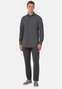Camisa gris de manga larga y botones con cuello extendido, combinada con pantalones grises y zapatos slip-on, con una textura suave y un ajuste a medida.