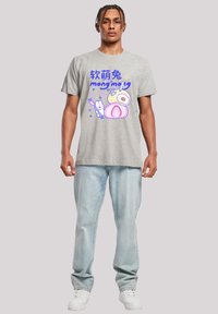 Grey graphic t-shirt featuring a cartoon design with text in blue and purple shades. Paired with light blue jeans and white sneakers.
