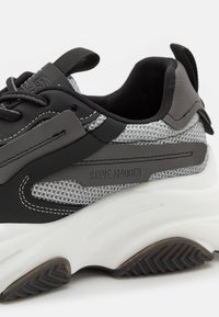 Black and gray sneaker featuring mesh and synthetic materials, thick white sole, lace closure, with rubber accents and visible branding.