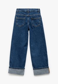 Sininen denimi, löysä sovitus, korkea vyötärö, käärityt lahkeet ja kaksi takataskua. Kankaassa on hienovarainen tekstuuri ja kulumisen yksityiskohtia.