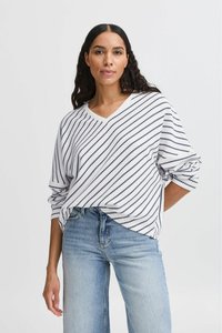 Weißer, gestreifter Langarmpullover mit V-Ausschnitt und losem Schnitt, mit marineblauen Linien. Kombiniert mit hellblauen, hochgeschnittenen Jeans.