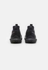Zwarte sportieve schoenen met een hoge schacht, voorzien van textuurstof en een gladde zool, verfraaid met reflecterende details en trektips.