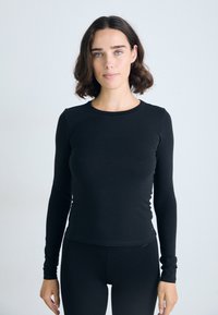 Zwarte longsleeve top gemaakt van rekbaar materiaal, met een ronde halslijn en een getailleerd ontwerp. Gladde textuur zonder zichtbare patronen of hardware.
