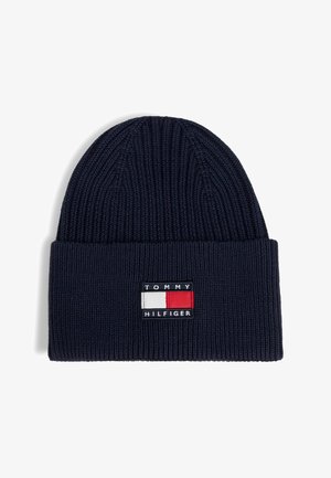 Granatowa dzianinowa czapka z wywiniętym mankietem, z prostokątną naszywką z logo Tommy Hilfiger w kolorach czerwonym, białym i granatowym.