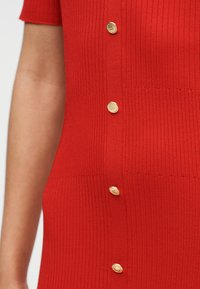 Κόκκινο ριγωτό φόρεμα με κοντά μανίκια, που διαθέτει χρυσά κουμπιά μπροστά για επιπλέον λεπτομέρεια και υφή.