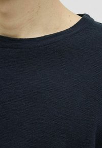 Granatowy sweter dzianinowy o teksturowanym wykończeniu, z okrągłym dekoltem i krótkimi rękawami, prezentujący szczegóły tkaniny i szwy.