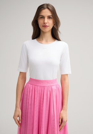Witte kortekleurige t-shirt met ronde halslijn, gecombineerd met een vloeiende, roze geplooide rok met een gestructureerde tailleband met branding.