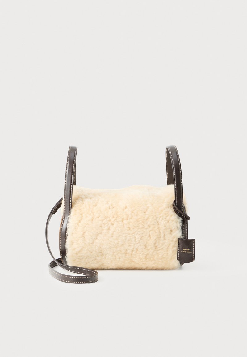 Μπεζ τσάντα ώμου από γούνα με καφέ δερμάτινο λουρί και λεπτομέρειες. Ορθογώνιο σχήμα με απαλό υφάσμα και ετικέτα με το εμπορικό σήμα.