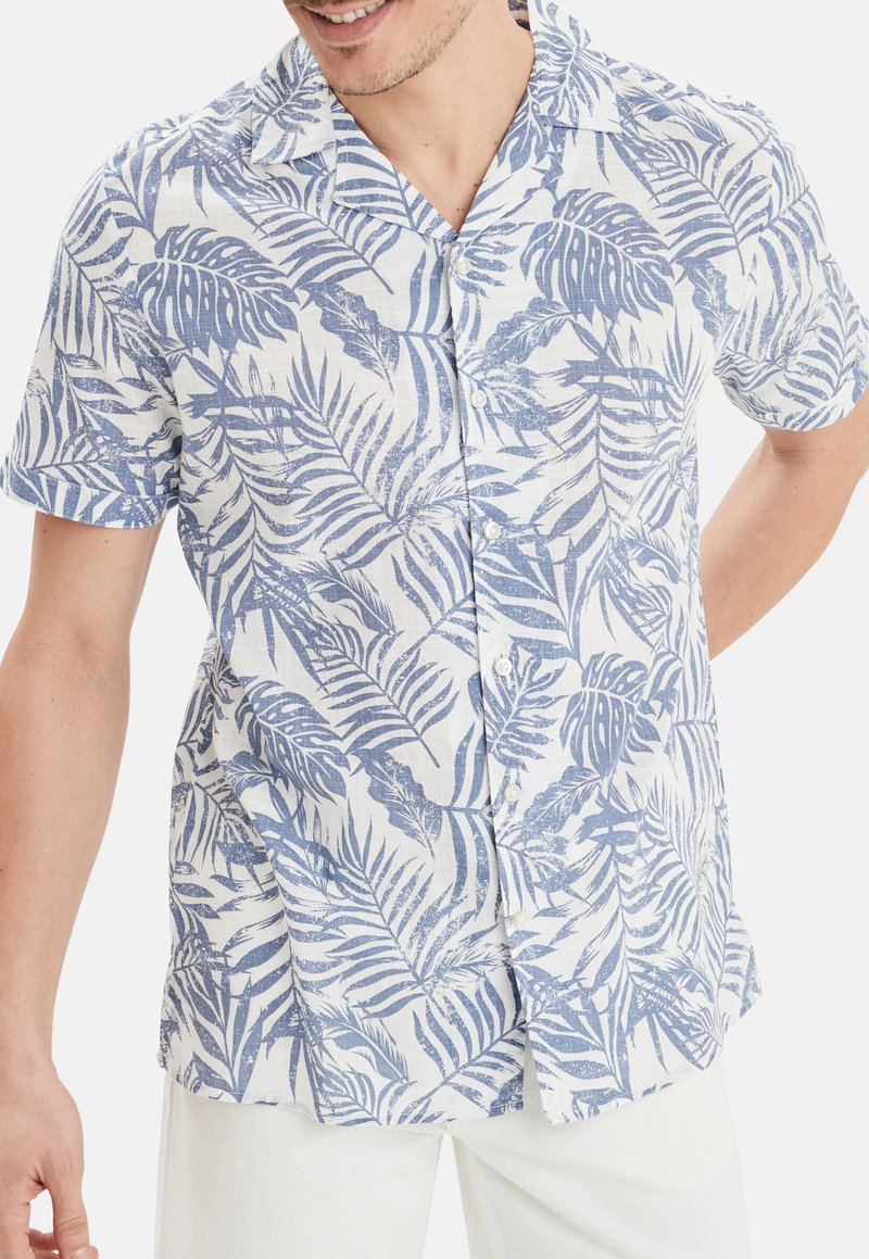 Camisa de manga corta de tela ligera, con un estampado de palmas azules en un fondo blanco. Botones destacados y un corte relajado.