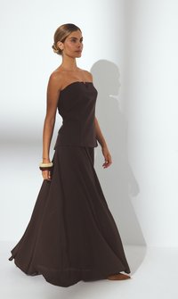 Rihmavaba, pruun kaksiosaline komplekt, millel on figuuri rõhutav ülemine osa ja voogav seelik. Sile, matt kangas ja mugav lõige. Lihtne disain ja elegante silhouette.