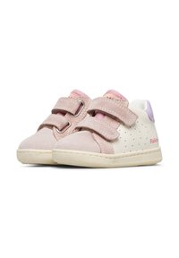 Pár dětských tenisek v béžové a růžové barvě s dvojitými suchými zipy a gumovými podrážkami, zobrazené na bílém pozadí.