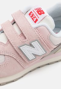 Baskets en suède rose clair avec une semelle en caoutchouc blanche, des accents en maille et un logo N texturé. Sangle Velcro pour un enfilage facile.
