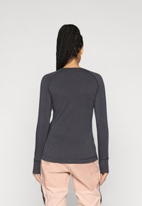 Paita pitkähihaisella tummanharmaalla värillä, pyöreällä pääntiellä, raglanhihoilla ja peukalonauhoilla hihoissa, yhdistettynä vaaleanpunaisiin housuihin. Tasainen pinta.