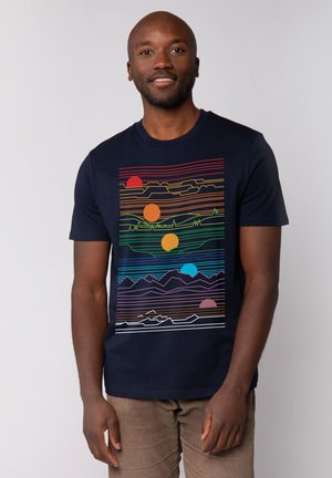 Marineblauwe t-shirt met een grafische print van gekleurde zonnen en bergen met horizontale lijnen in verschillende kleuren. Korte mouwen en ronde hals.