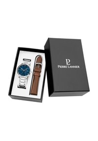 Reloj de acero inoxidable con una esfera azul, eslabones plateados y una correa de cuero marrón, presentado en una caja negra con el nombre de la marca.