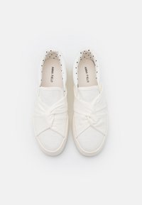 Weiße Slip-On-Leinensneaker mit verdrehtem Stoffdetail und schwarzem Punktenfutter, Marke "Anna Field" ist in jedem Schuh sichtbar.