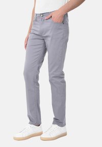 Pantaloni grigi chiari dal taglio slim, realizzati in morbido cotone. Presentano tasche e chiusura con bottone, abbinati a sneakers bianche.