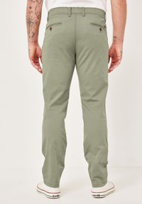 Grüne Hose aus Baumwollmischgewebe, mit zwei Gesäßtaschen und braunen Knopfakzenten sowie einem geraden Bein.