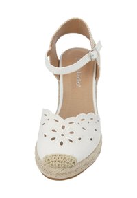 Witte canvas espadrille met een uitgesneden bloemenontwerp op de bovenzijde, gevlochten jute hak en een beige haakaccent op de teen. Verstelbare enkelband.
