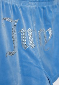 Pantaloni shorts in velluto blu con abbellimenti in strass argento che formano la parola "Juicy" in un elegante carattere corsivo. Tessuto morbido, vestibilità comoda.