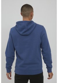 Felpa blu in cotone con cappuccio regolabile, dotata di tasca a marsupio, polsini e orlo a coste. Design semplice e pulito senza decorazioni.