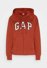Roestkleurige zip-up hoodie met voorzakken en wit "GAP" logo over de borst, met een capuchon met trekkoord.