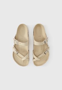 Μπεζ σανδάλια από συνθετικό υλικό με σταυρωτούς ιμάντες και δύο ρυθμιζόμενες μεταλλικές αγκράφες. Υφή στο πέλμα με αποτύπωση του λογότυπου της μάρκας.