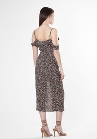 Schwarzes Blumen-Off-Shoulder-Kleid mit Rüschensleeves, taillierter Oberteil, fließendem Rock und beigen High-Heels.