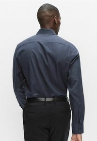 Marineblå mønstret skjorte med lange ærmer, knappede manchetter, standard krave og lige kant, kombineret med sorte bukser.