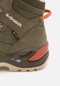 Grüner Wildlederschuh für Wanderungen mit GORE-TEX-Label, gepolstertem Kragen und leuchtend rotem Akzent an der Ferse, strukturiertem Sohlenprofil mit strapazierfähigem Tread-Muster.