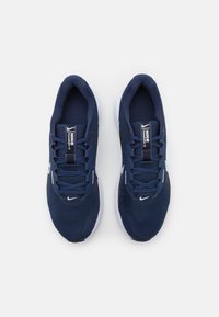 Tengerészkék sportcipők hálós felsőrésszel, lapos fűzőkkel, fehér talppal, és Nike logóval a nyelvén és az oldalán. Könnyű kialakítás jellemzi.
