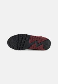 Sola de sapato Nike com uma base de borracha preta e um padrão de ranhura multidirecional proeminente. Detalhes em burgundy ao longo do lado e do calcanhar.
