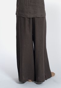 Pantaloni a gamba larga in lino marrone scuro. Tessuto morbido, lunghi fino a terra, con una vestibilità ampia. L'orlo è dritto con dettagli minimi.