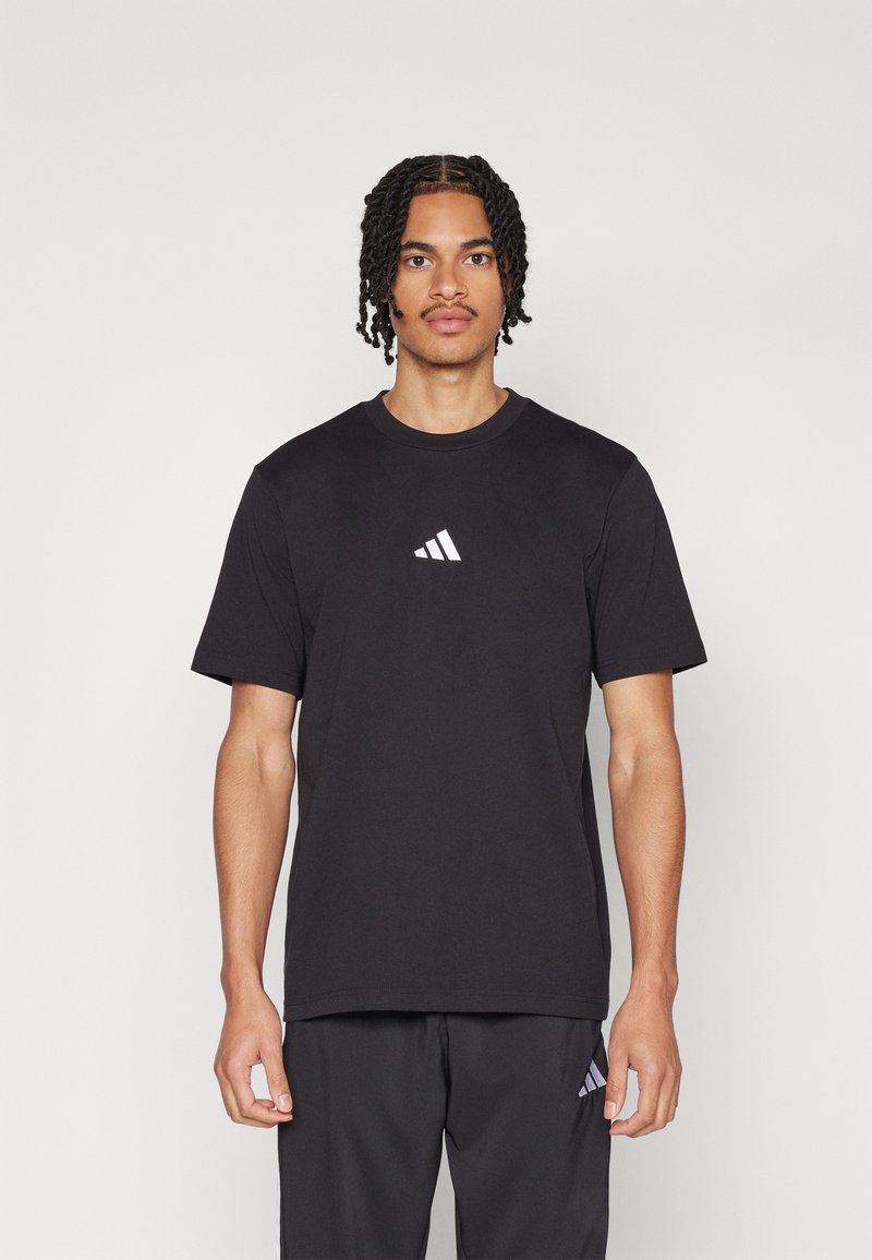 Zwarte katoenen t-shirt met een ronde hals en korte mouwen. Heeft een wit Adidas-logo in een klassiek driehoekig ontwerp op de borst.