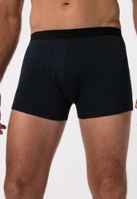 Černé boxerky vyrobené z měkké tkaniny s elastickým pasem, na kterém je jemné logo. Navrženo pro pohodlí a těsný střih.