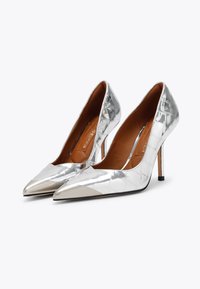 Pumps argentati con tacchi alti, superiori in pelle lucida a pelle di coccodrillo, punta affusolata e cappucci metallici. Interno in pelle marrone e tacchi a stiletto slanciati.