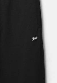 Zwarte joggingbroek van zachte katoen met een slim fit, voorzien van een zilveren logo aan de linkerkant en zijzakken.