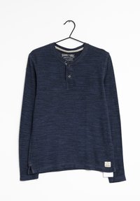 Námořnická modrá dlouhá halenka henley s texturovanou látkou, dvojitým knoflíkovým zapínáním a bočními rozparky na spodním okraji. Obsahuje označení značky na dolní straně.