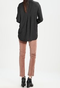 Černobílé kostkované dlouhé rukávy s skládaným zadním dílem, spárované s růžovými kordovými kalhotami a černými koženými kotníkovými botami na podpatku.