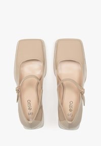 Nude lakierowane szpilki z kwadratowym noskiem, z paskiem wokół kostki i minimalistycznym wzornictwem. Często stosowane na formalne okazje i wydarzenia.