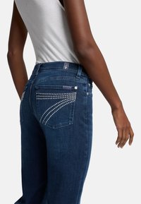 Donkerblauwe denim jeans met versierde achterzakken met steentjes, rechte pijpen en een middelhoge taille.