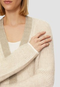 Beige gestrickte Strickjacke mit einem kontrastierenden grauen V-Ausschnitt. Verfügt über eine gerippte Textur und lange Ärmel, die einen weichen Stoff und eine entspannte Passform zeigen.
