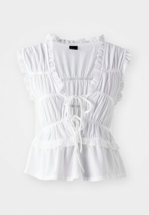 White blouse featuring ruffled short sleeves, textured fabric, a deep V-neck with a tie front, and tiered frill detailing at the hem.