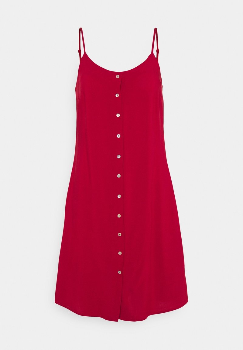 Robe rouge sans manches arrivant aux genoux, avec des bretelles fines et une rangée frontale de petits boutons ronds.